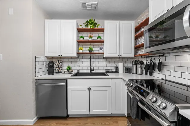 a kitchen with stainless steel appliances a stove a sink cabinets and a window