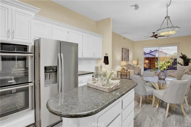 a kitchen with granite countertop a table chairs refrigerator and microwave