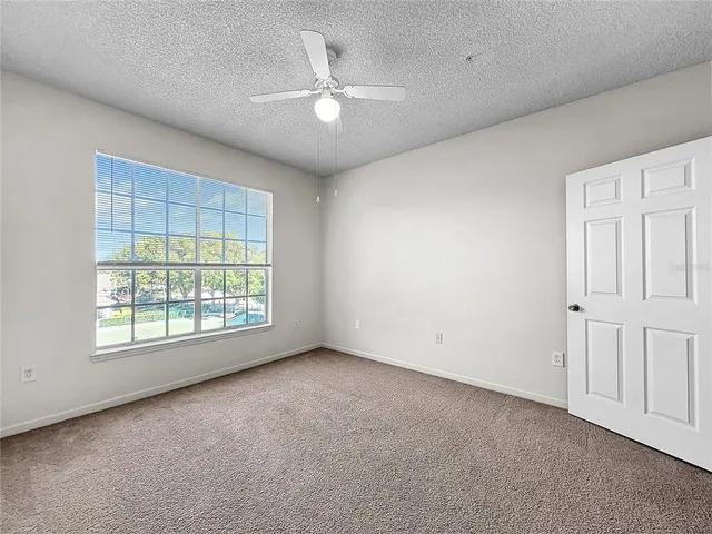 an empty room with windows and chandelier fan