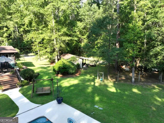 a living room with chairs flat screen tv and a large window