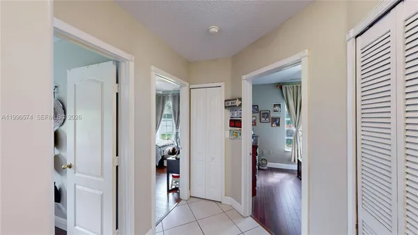 a view of an empty room with wooden floor and fan