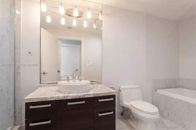 a bathroom with a granite countertop sink a toilet and a mirror
