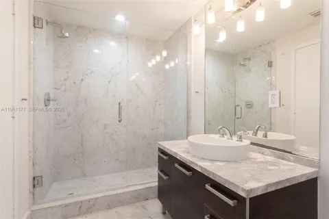 a bathroom with a granite countertop sink a shower and a mirror