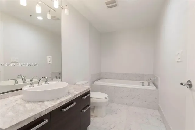 a bathroom with a granite countertop sink a toilet and bathtub