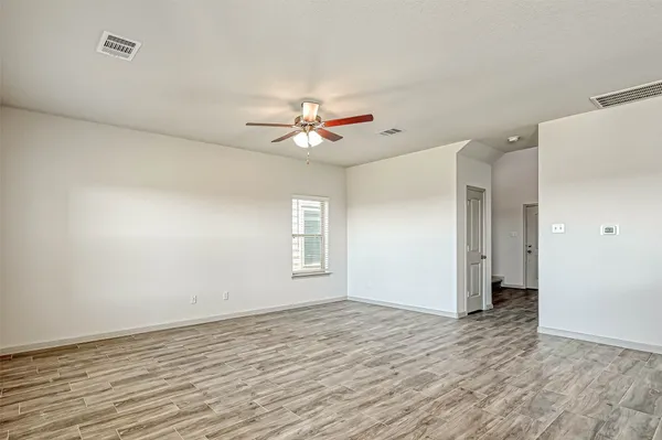 an empty room with wooden floor and ceiling fan