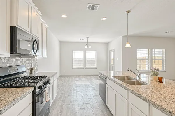 a kitchen with stainless steel appliances granite countertop a sink stove and cabinets