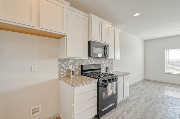a kitchen with stainless steel appliances white cabinets and a stove top oven