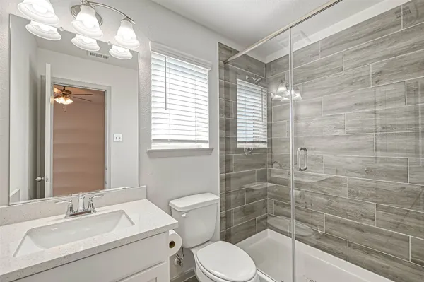 an empty room with windows and ceiling fan