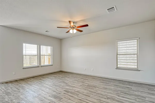 a view of empty room with wooden floor and fan