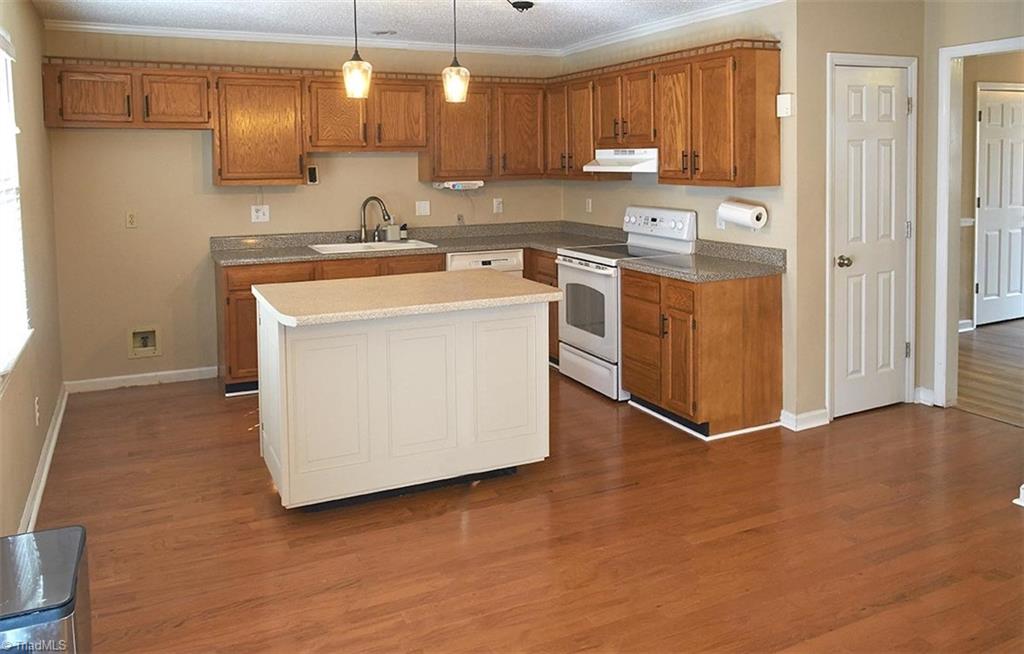 1012 Springwood Lane Archdale, NC 27370 - Photo 11 of 46 Open kitchen with oak cabinets and a free standing island that will remain. Hardwood floors in the kitchen and dining room.