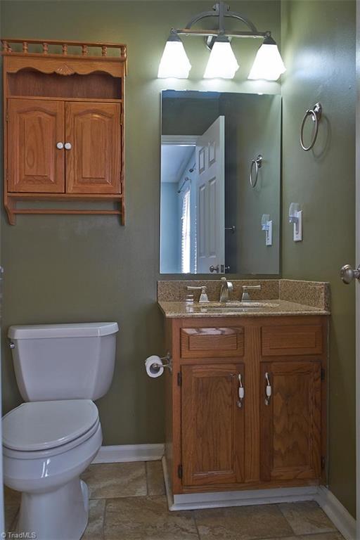 1012 Springwood Lane Archdale, NC 27370 - Photo 28 of 46 Primary bathroom has oak cabinets, granite counter top and glazed porcelain tile floors.