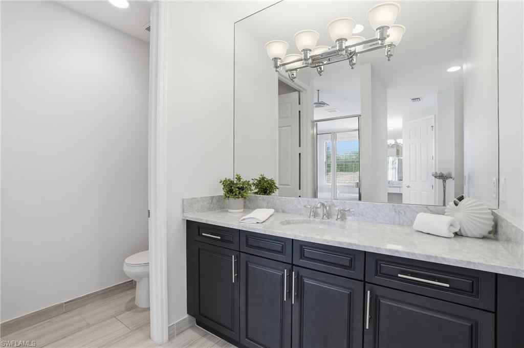 13768 Luna Drive Naples, FL 34109 - Photo 24 of 44 a bathroom with a granite countertop sink a toilet and a mirror