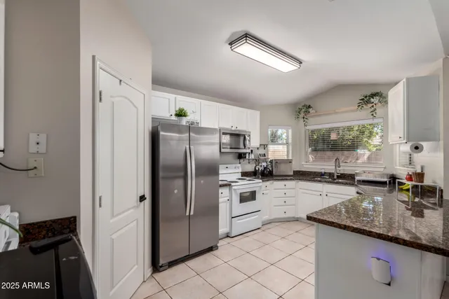 a kitchen with granite countertop a sink appliances cabinets and counter space