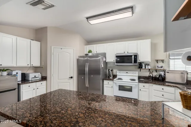 a kitchen with stainless steel appliances kitchen island granite countertop a refrigerator stove and sink
