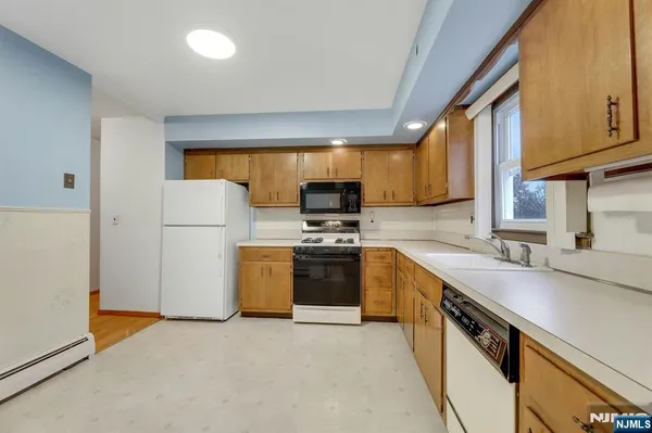 a kitchen with a sink a stove top oven a refrigerator a counter top space and cabinets