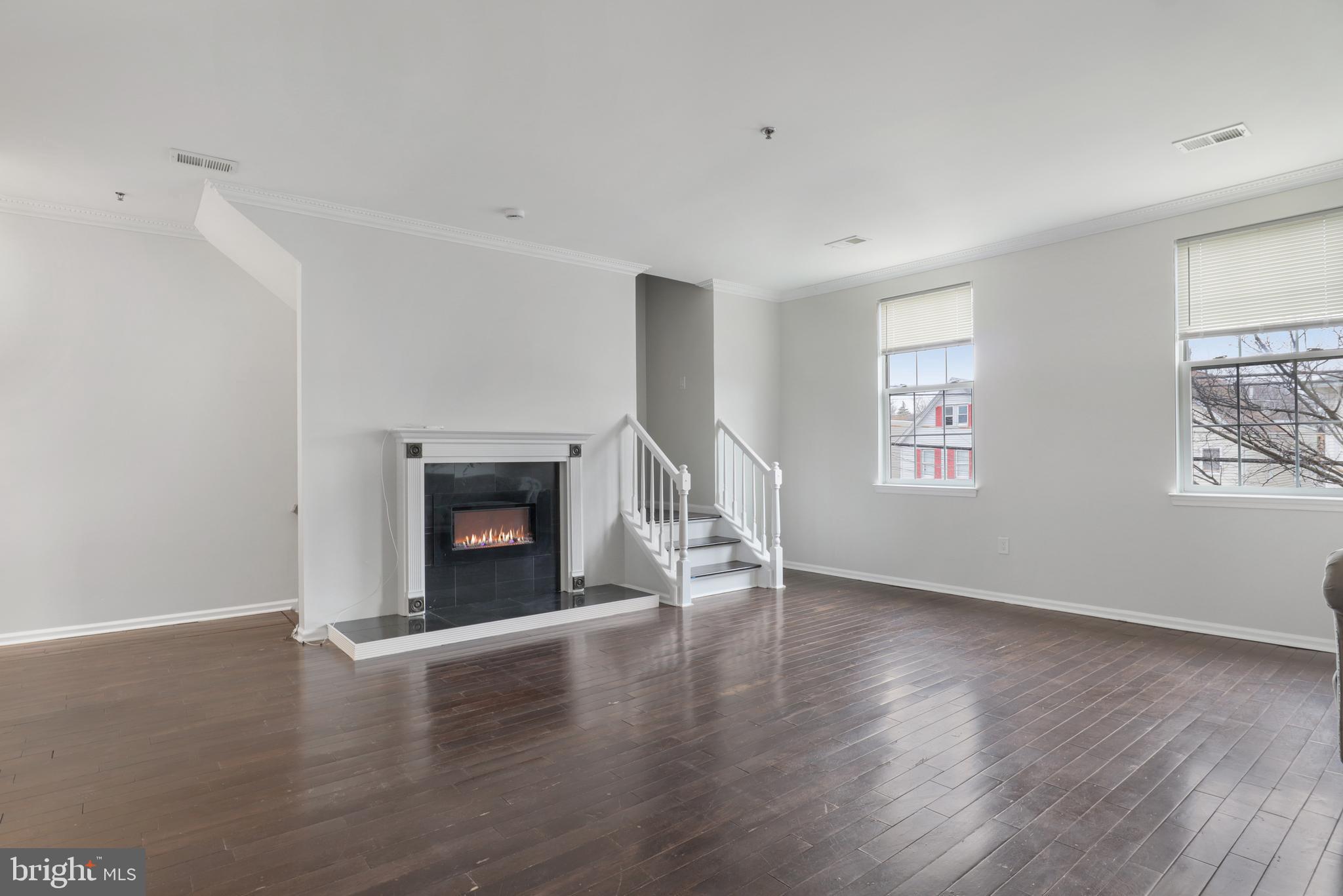 130B Remsen Avenue New Brunswick, NJ 08901 - Photo 7 of 33 an empty room with wooden floor a fireplace and windows