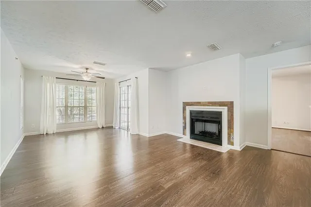 an empty room with wooden floor fireplace and windows