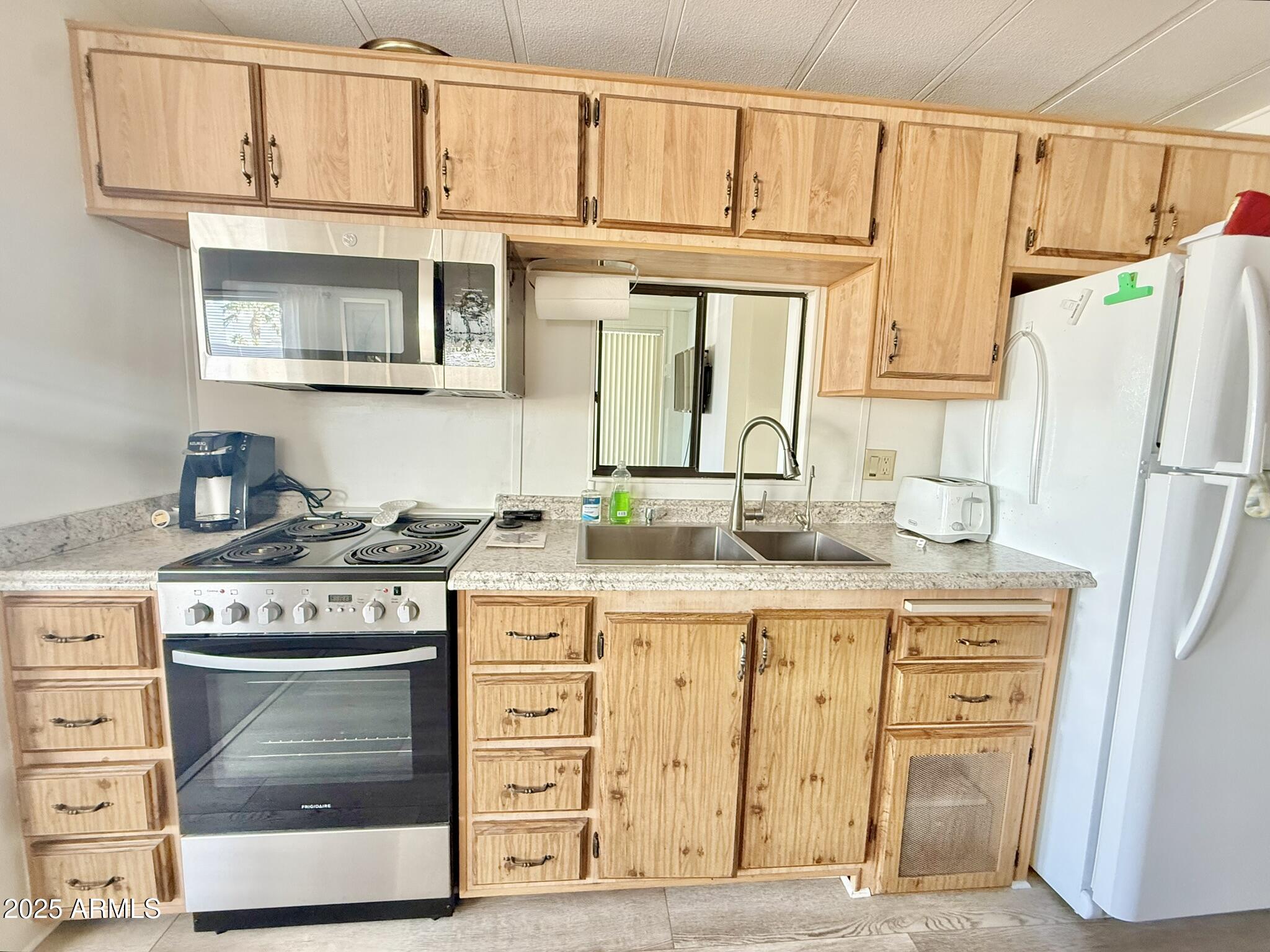 8865 East Baseline Road, Unit 1643 Mesa, AZ 85209 - Photo 10 of 44 a kitchen with stainless steel appliances granite countertop a stove and a white cabinet