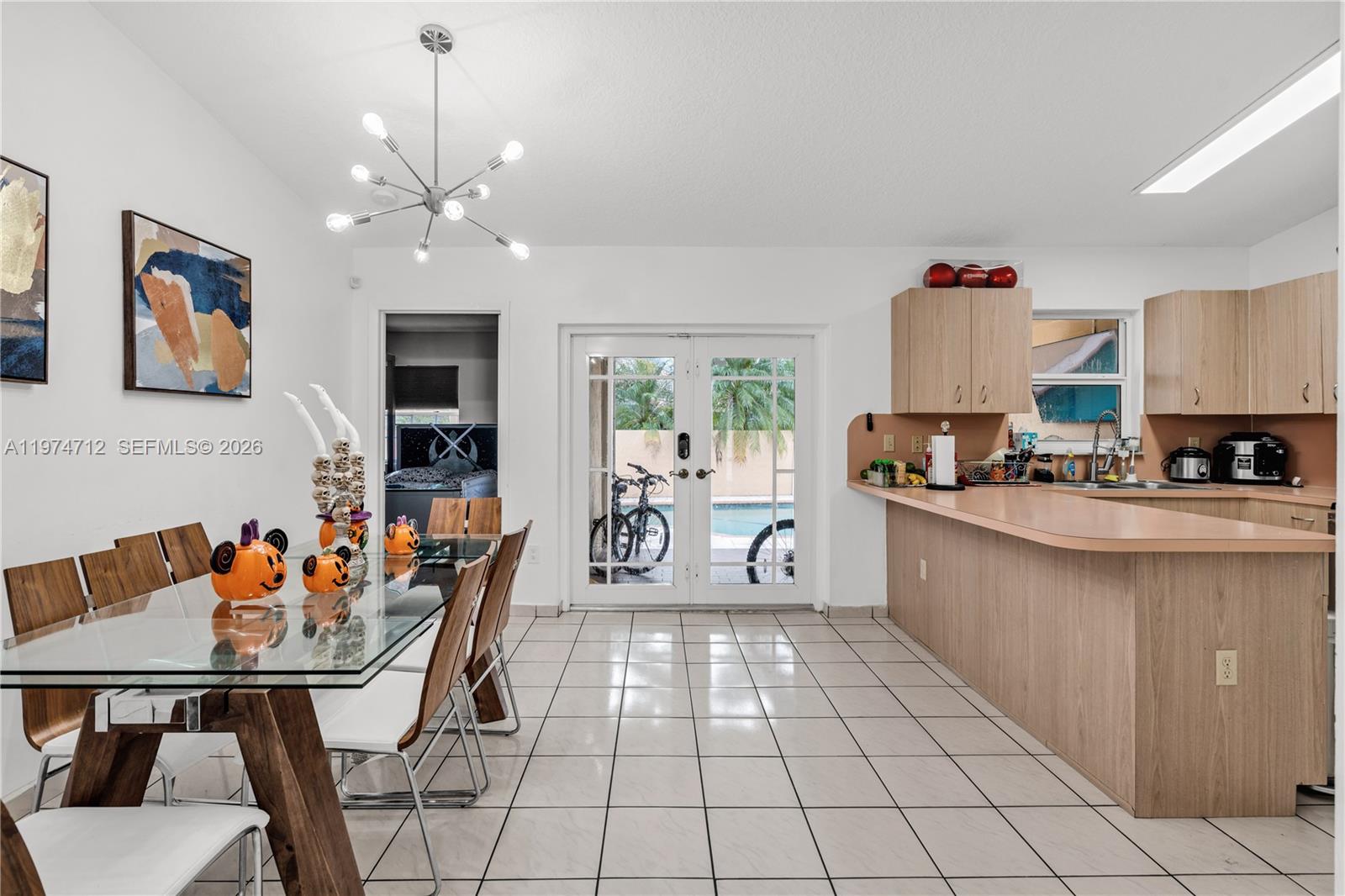 12775 Southwest 59th Street Miami, FL 33183 - Photo 8 of 18 a kitchen with stainless steel appliances kitchen island granite countertop a table chairs in it and wooden floors