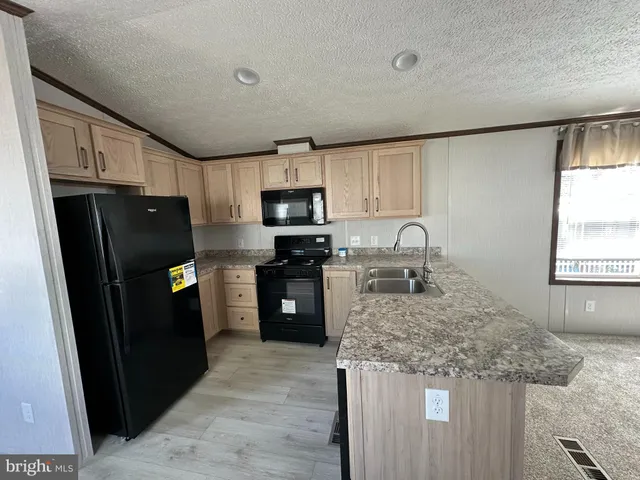 a kitchen with granite countertop a refrigerator stove and sink