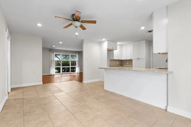 a kitchen with granite countertop a sink white cabinets and stainless steel appliances