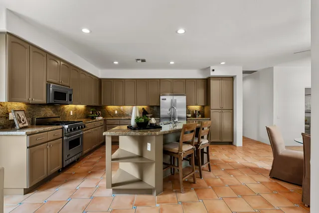 a kitchen with stainless steel appliances granite countertop a sink a stove a dining table and chairs