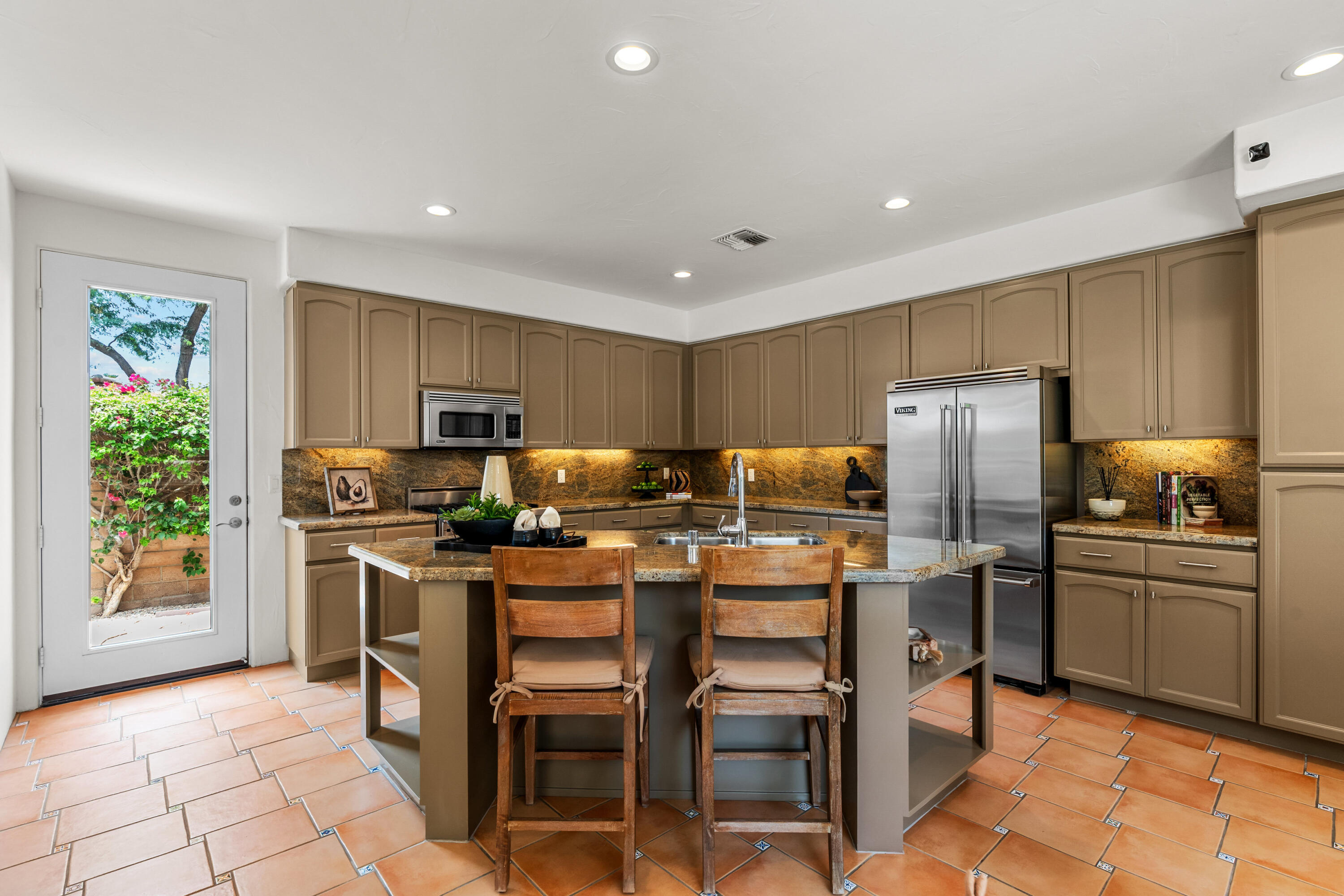 78900 Rio Seco La Quinta, CA 92253 - Photo 14 of 48 a kitchen with stainless steel appliances kitchen island granite countertop a table chairs and a refrigerator