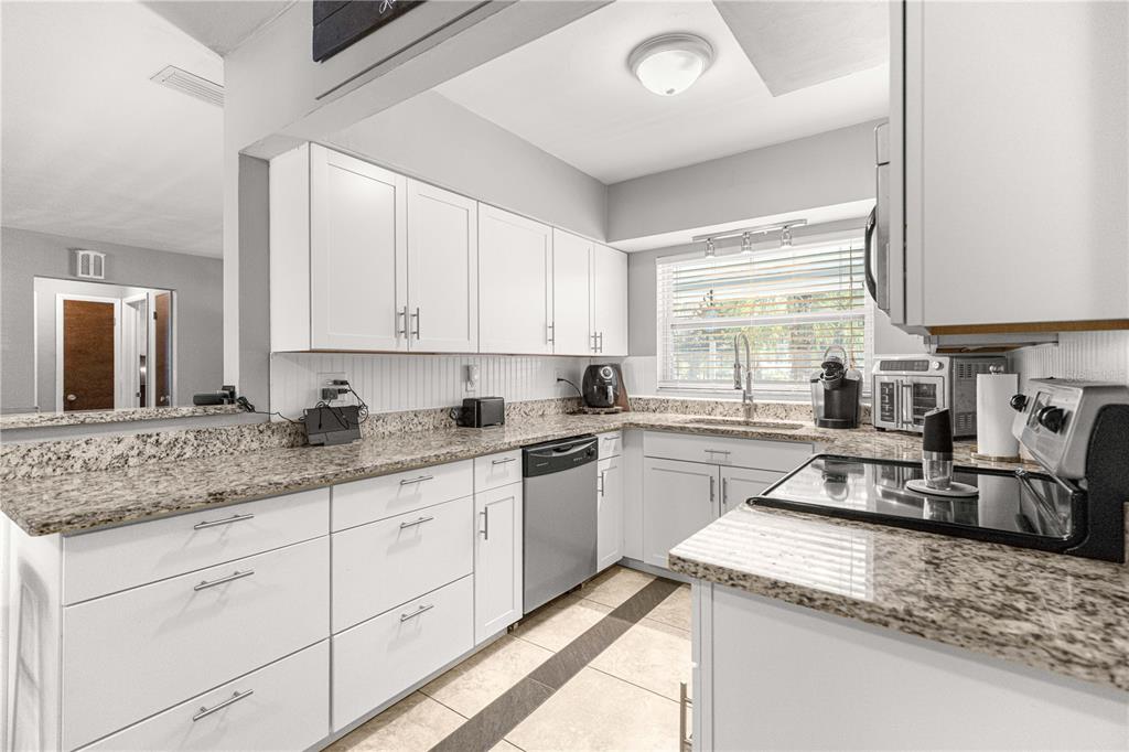 6401 East Holly Street Inverness, FL 34452 - Photo 13 of 51 a kitchen with granite countertop a sink stove and cabinets