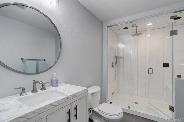 a bathroom with a granite countertop sink toilet mirror vanity and shower