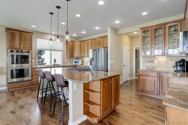 a kitchen with stainless steel appliances kitchen island granite countertop a table chairs stove and refrigerator