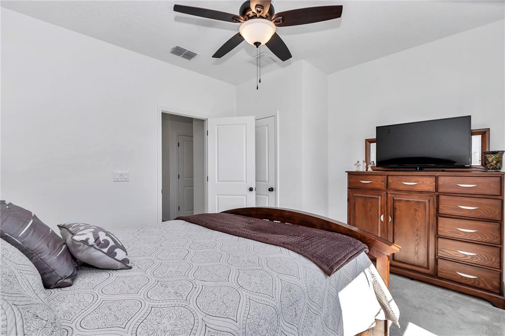 7651 Southwest 74th Loop Ocala, FL 34481 - Photo 32 of 47 a bedroom with a bed and a flat tv screen on dresser