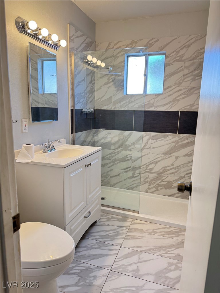 350 East Desert Inn Road, Unit F104 Las Vegas, NV 89109 - Photo 2 of 27 Full bath featuring light marble finish floors, a marble finish shower, and vanity