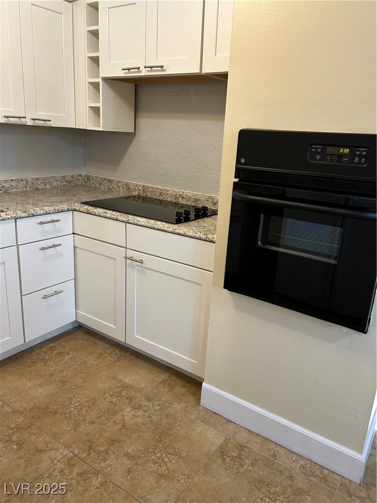 350 East Desert Inn Road, Unit F104 Las Vegas, NV 89109 - Photo 4 of 27 Kitchen featuring a textured wall, wall oven, white cabinets, open shelves, and black stovetop