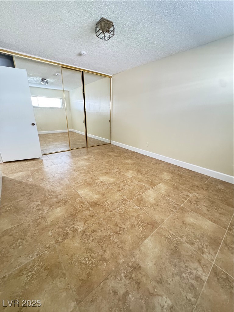 350 East Desert Inn Road, Unit F104 Las Vegas, NV 89109 - Photo 7 of 27 Unfurnished bedroom with a textured ceiling and a closet