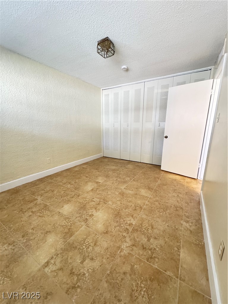 350 East Desert Inn Road, Unit F104 Las Vegas, NV 89109 - Photo 8 of 27 Unfurnished bedroom with a textured wall and a textured ceiling