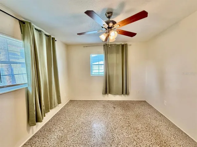 an empty room with windows and fan