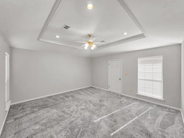 an empty room with windows and ceiling fan
