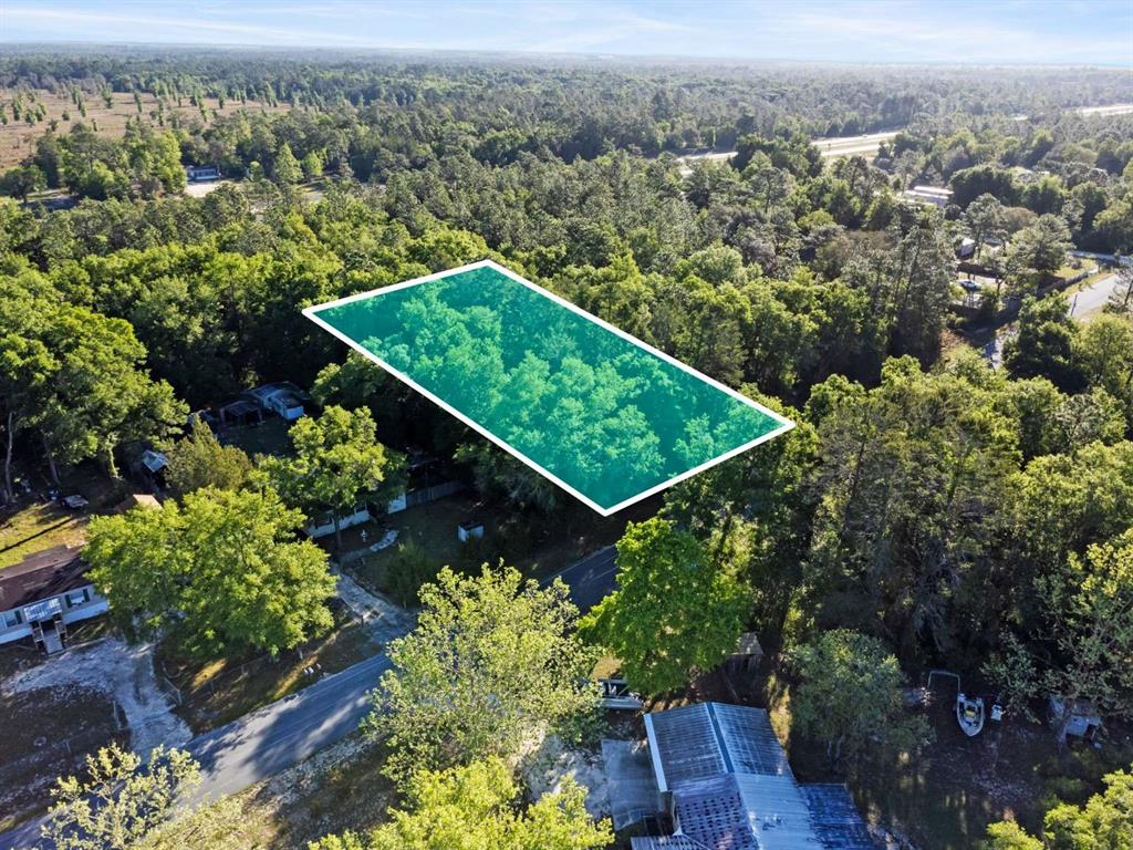 an aerial view of a residential houses with outdoor space and trees all around
