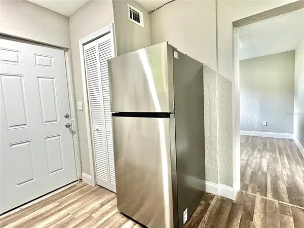 a view of a refrigerator in kitchen and an empty room