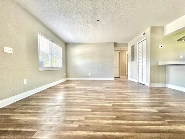 a view of an empty room with window and wooden floor