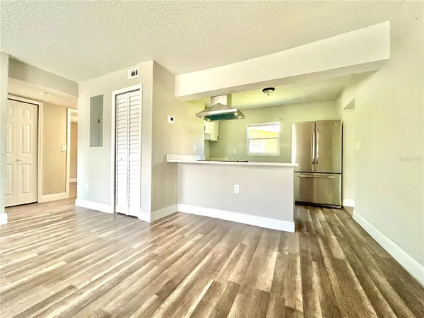 a view of a hallway with wooden floor and a kitchen