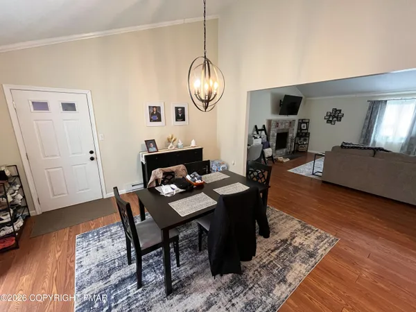 a dining room with wooden floor a chandelier a wooden table and chairs