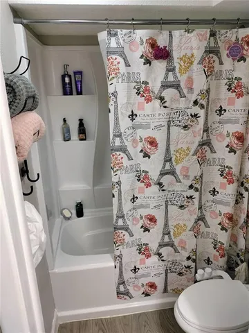 a view of an empty room with wooden floor and a kitchen