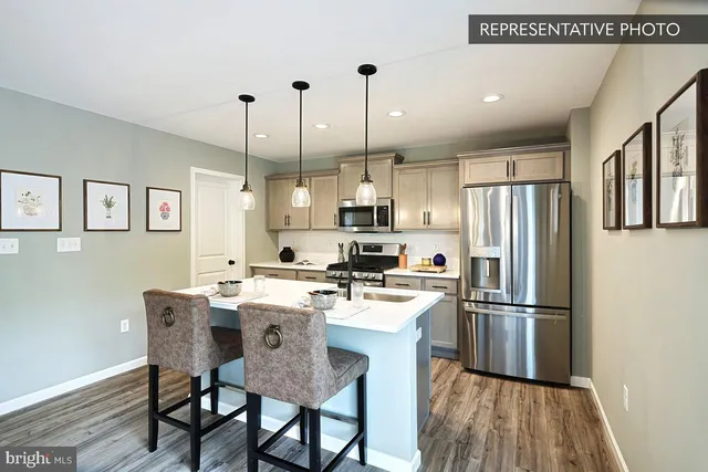 a kitchen with stainless steel appliances a dining table chairs refrigerator and sink