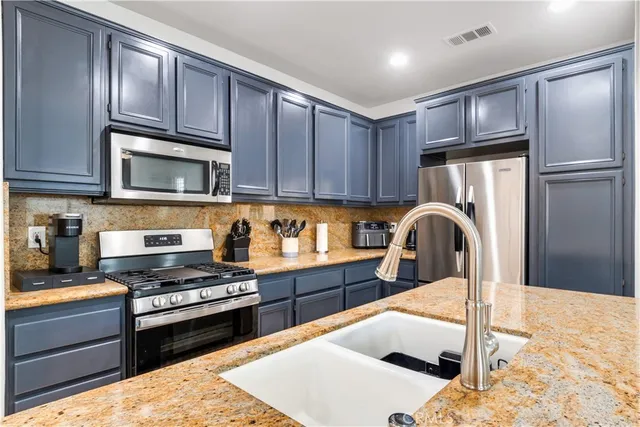 a kitchen with stainless steel appliances wooden cabinets a stove a sink and a refrigerator