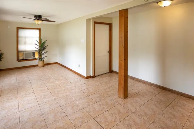 a view of an empty room with window and chandelier fan