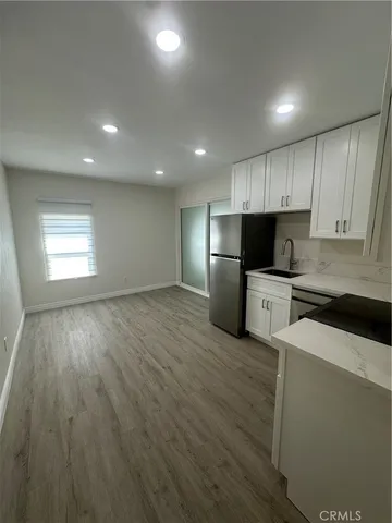 a kitchen with granite countertop wooden floors stainless steel appliances and white cabinets