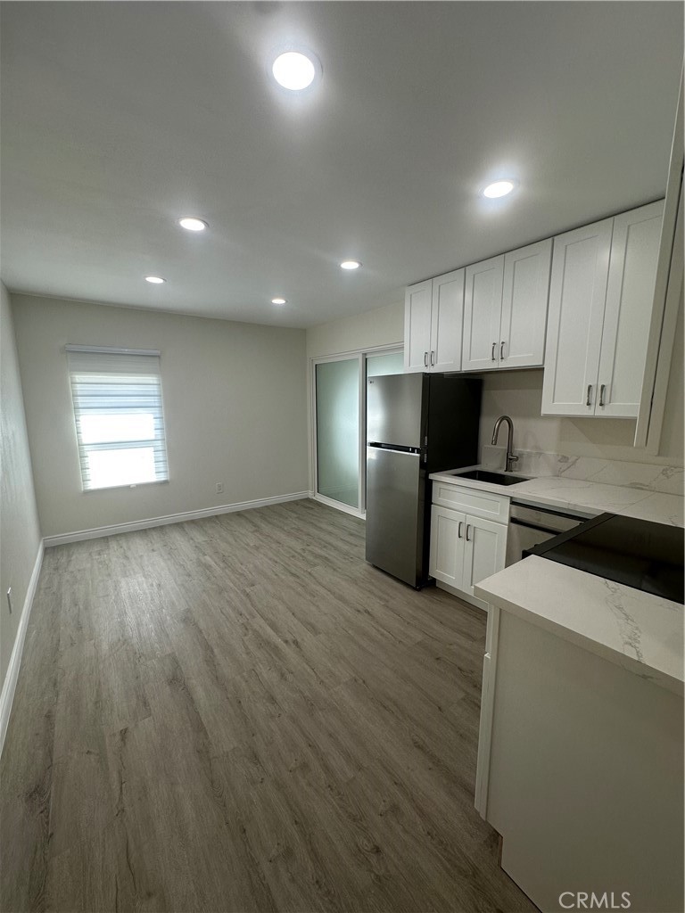 20655 Lemmer Street Chatsworth, CA 91311 - Photo 7 of 25 a kitchen with granite countertop wooden floors stainless steel appliances and white cabinets