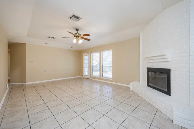 a view of an empty room with chandelier fan