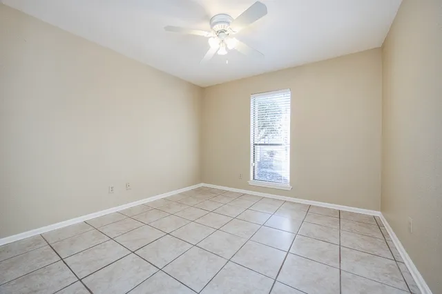 a view of an empty room and chandelier fan